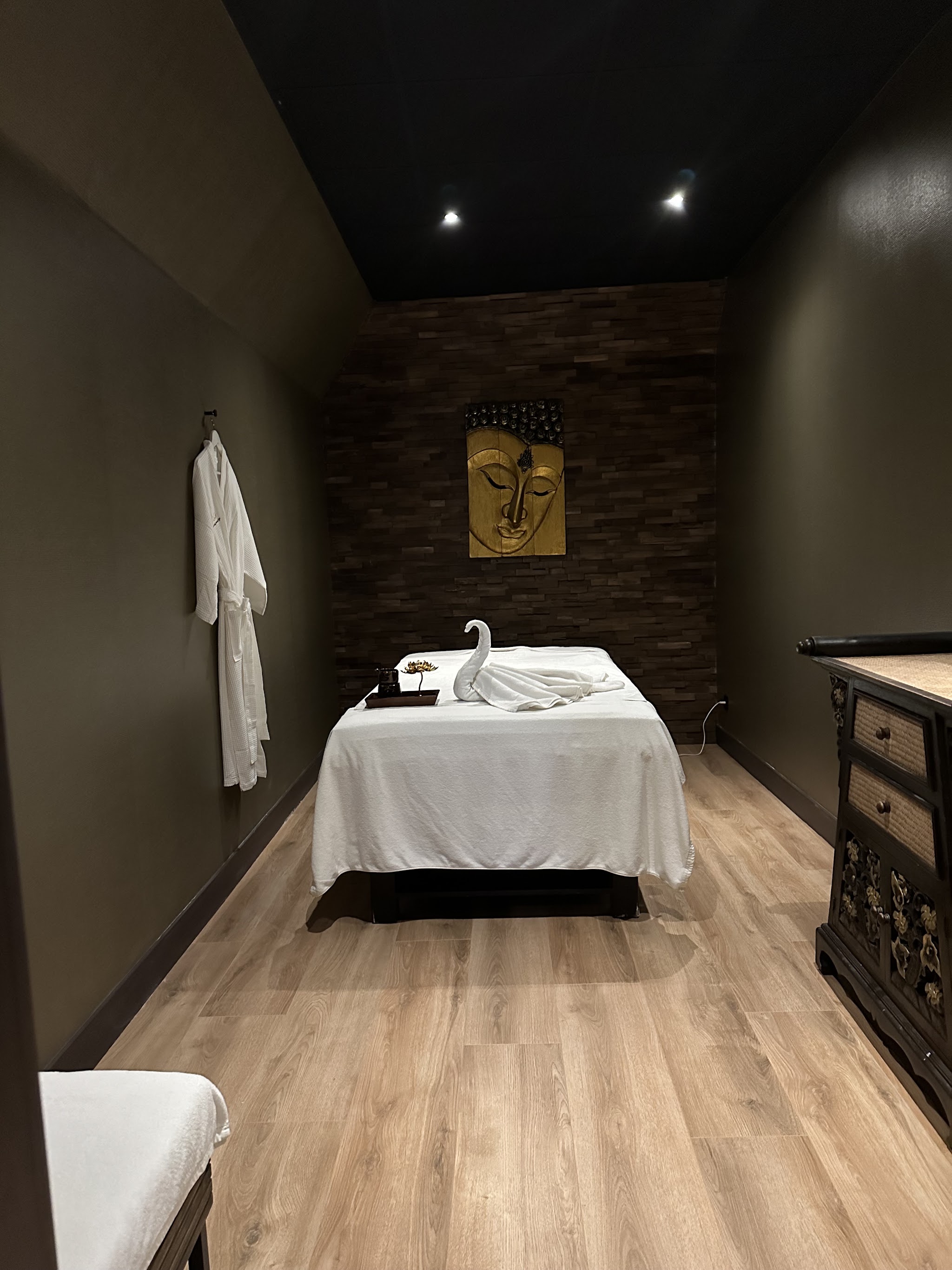 Afgewerkte massagekamer met zacht licht en een wit massagebed